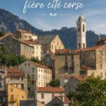 Vue panoramique sur la citadelle de Corte en Corse, entourée de montagnes et de verdure.
