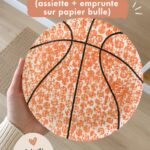 Un ballon de basket unique créé à partir d'une assiette et d'une empreinte sur papier bulle, idéal pour une activité manuelle en famille.